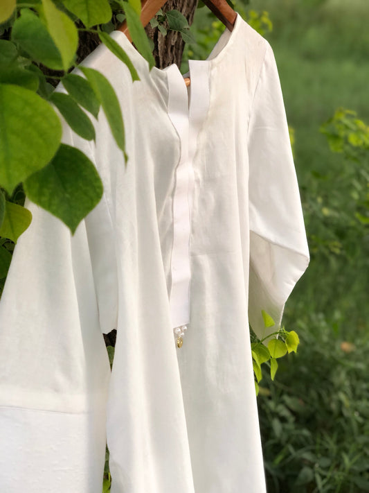White shirt hanging on a tree branch with green leaves in the background