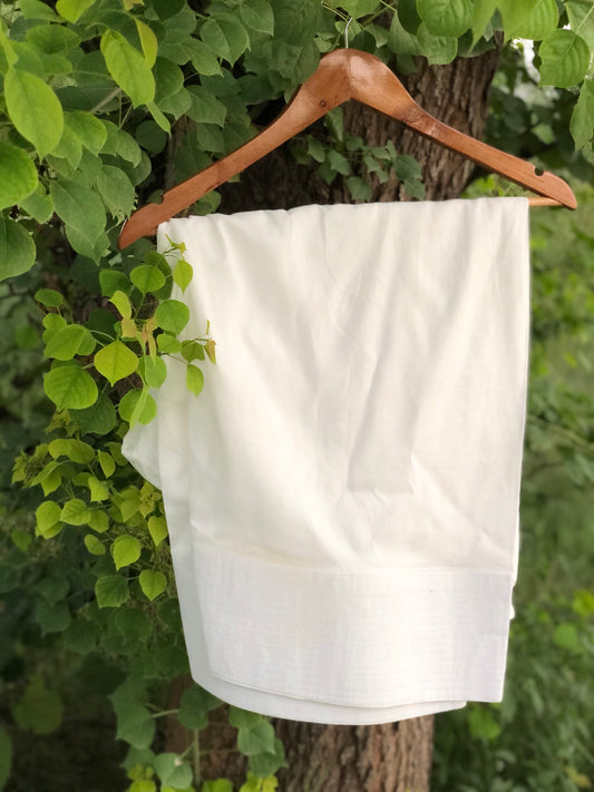 White towel hanging on a wooden hanger against a green leafy background