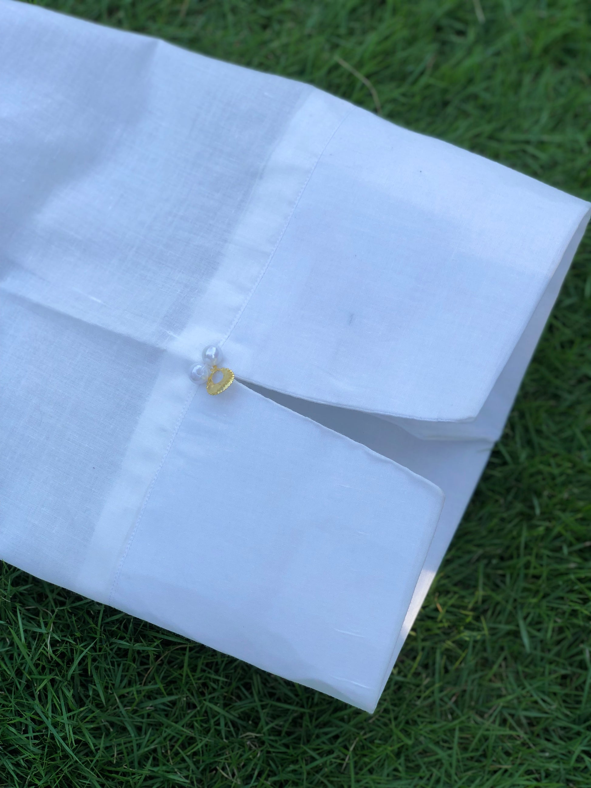 White shirt with a gold button on grass