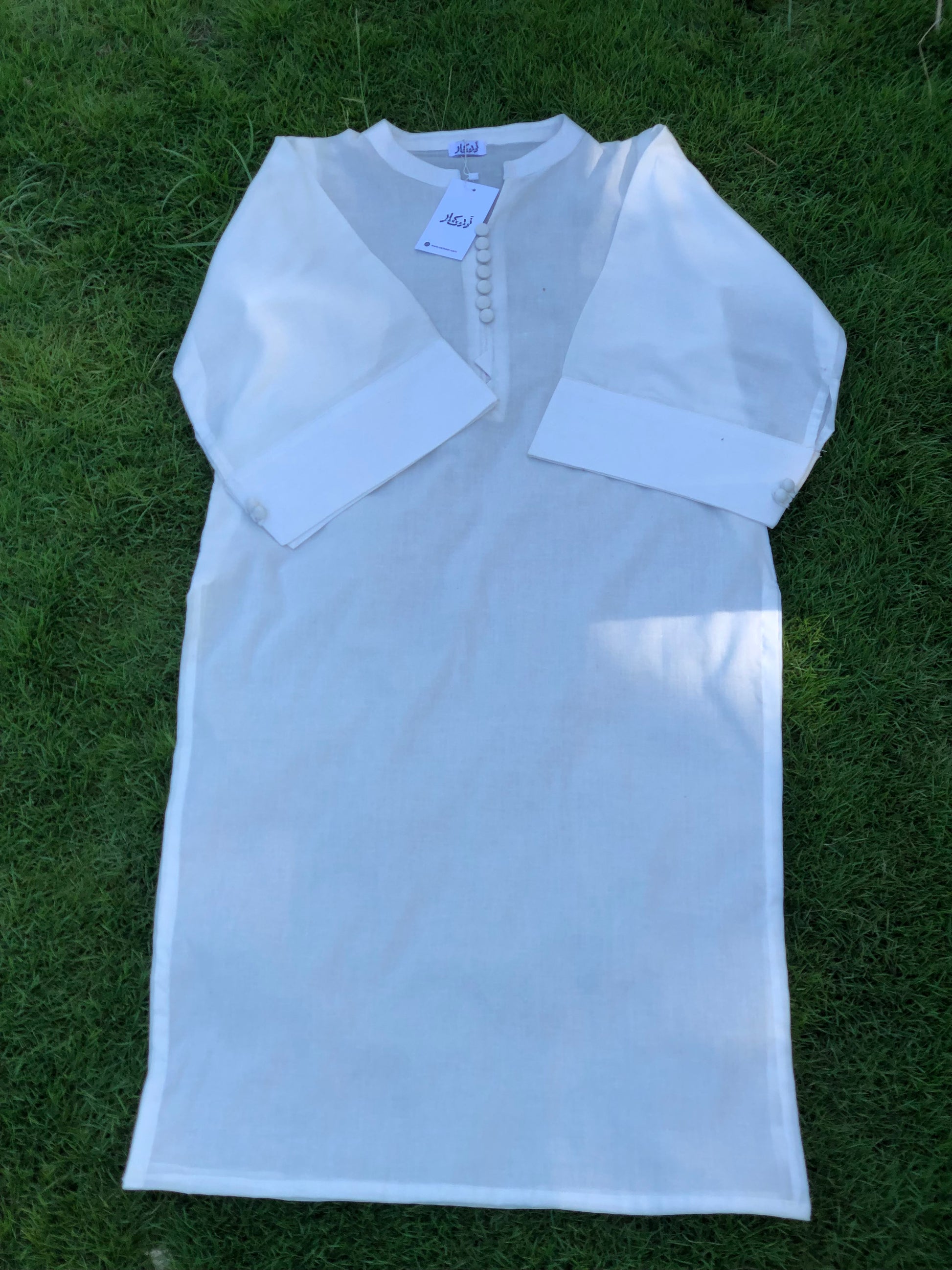 White dress with sheer sleeves on a grassy background