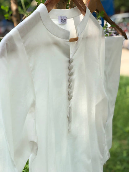 White blouse with buttons on a hanger against a blurred outdoor background