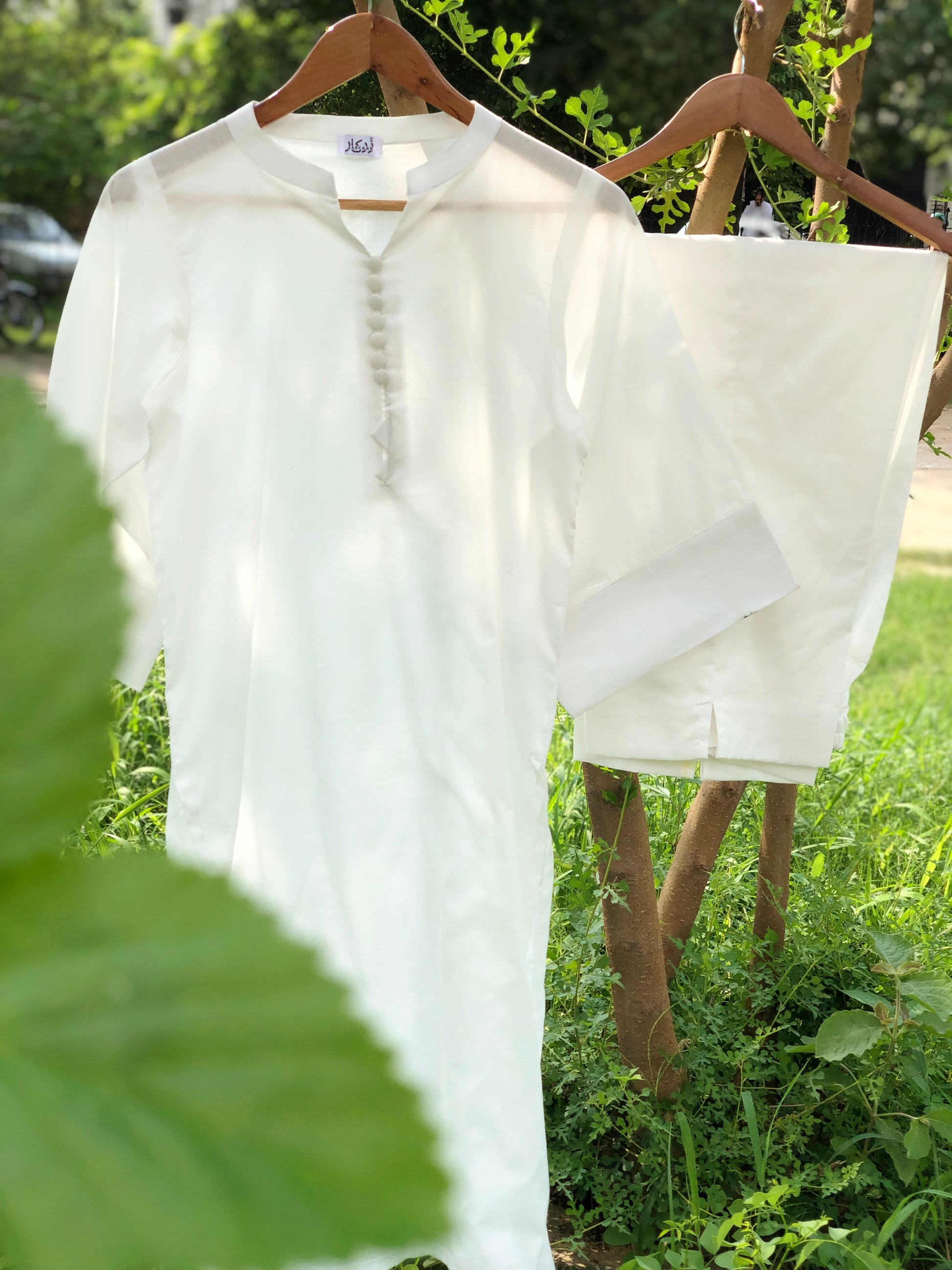 White shirt and shorts on hangers against a natural background